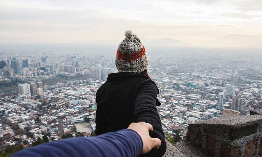 Two people holding hands, looking over the city.